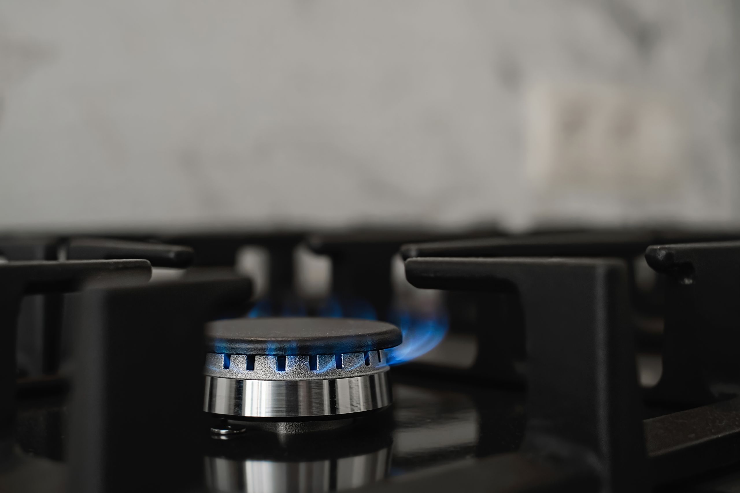 Modern kitchen stove, natural gas burns with a blue flame. Household gas consumption. Close-up, selective focus